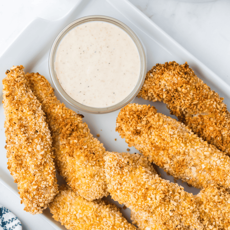Golden, crispy Whataburger-style chicken strips on a plate with dipping sauce.