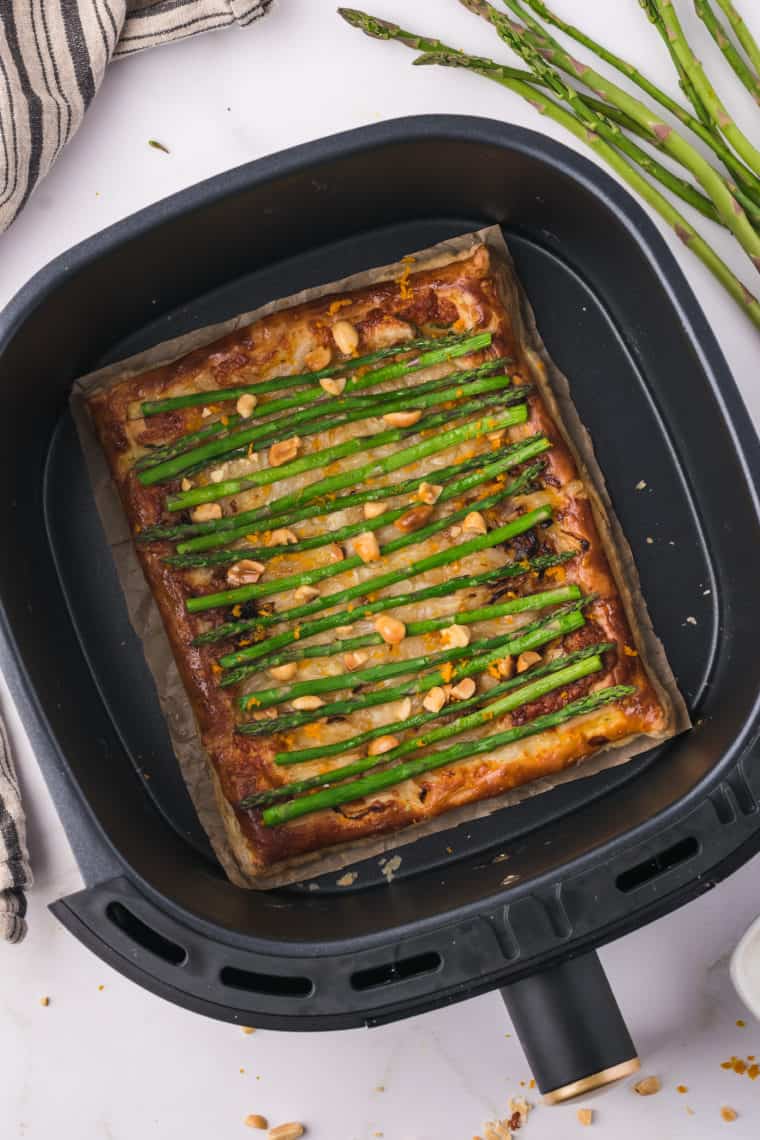 Golden air fryer asparagus tart with cheese, sautéed onions, and fresh herbs.