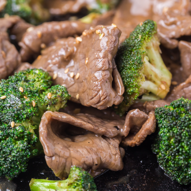 Finished Blackstone beef and broccoli topped with chopped green onions, served hot and ready to eat.
