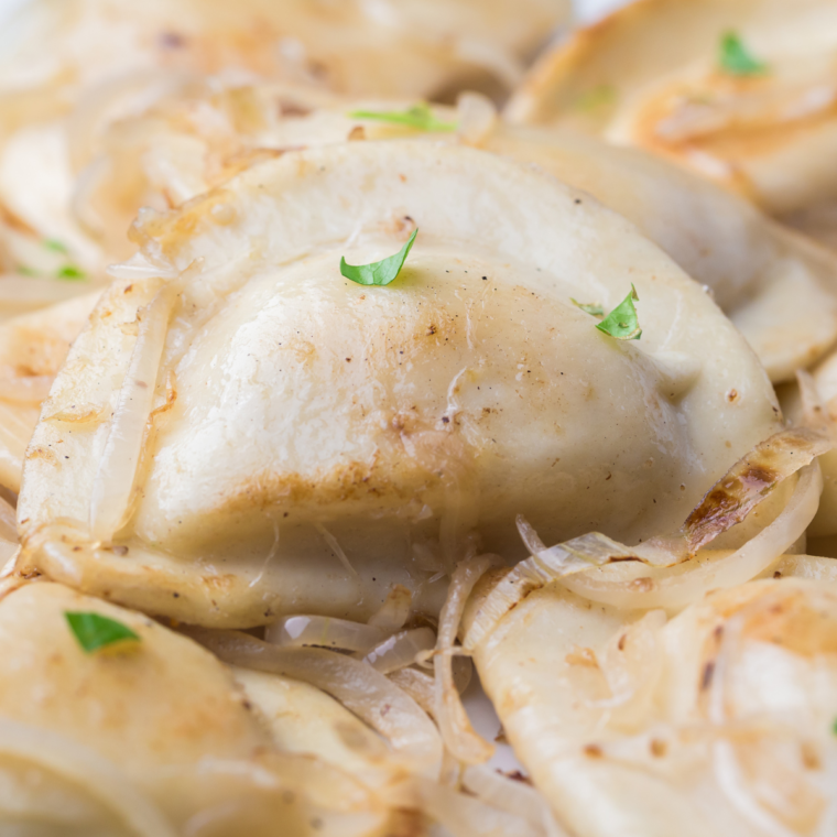 Blackstone pierogies and onions cooked golden brown on a griddle, ready to serve.