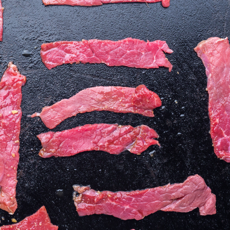 Marinated steak strips searing on a hot Blackstone griddle