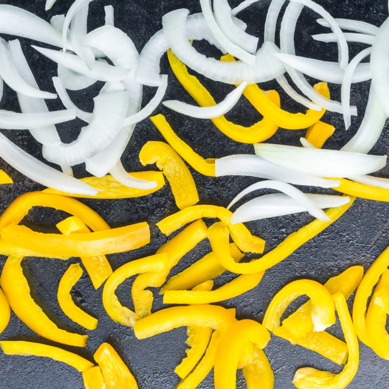 Bell peppers, onions, and mushrooms stir-frying on the griddle
