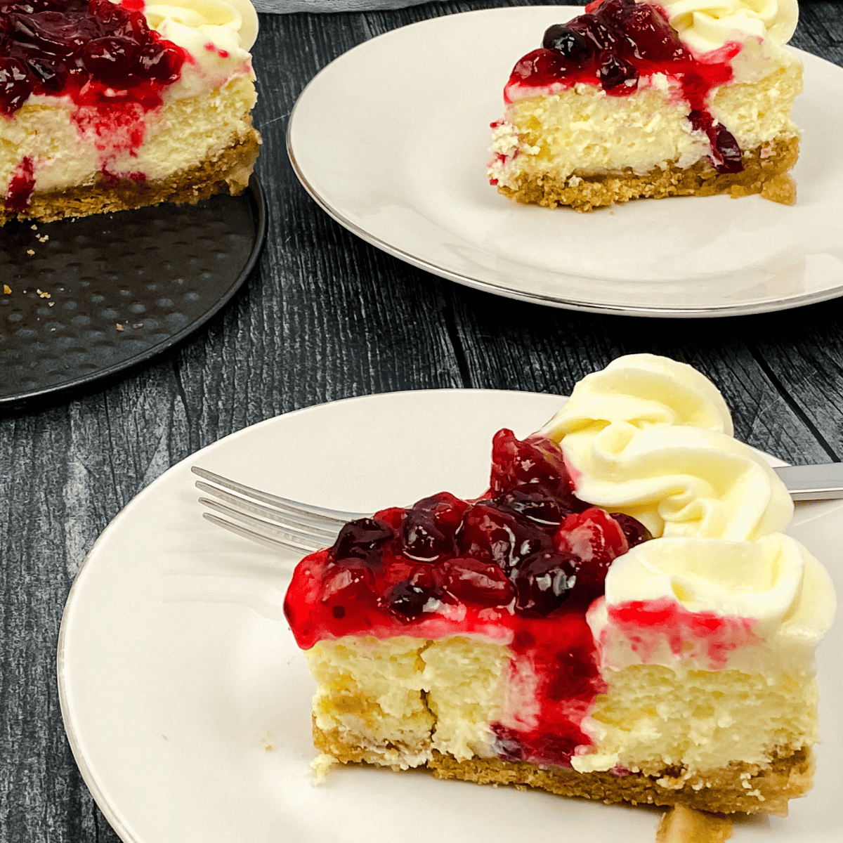 Slice of Cheesecake Factory-style cranberry cheesecake with vibrant red topping on a dessert plate.