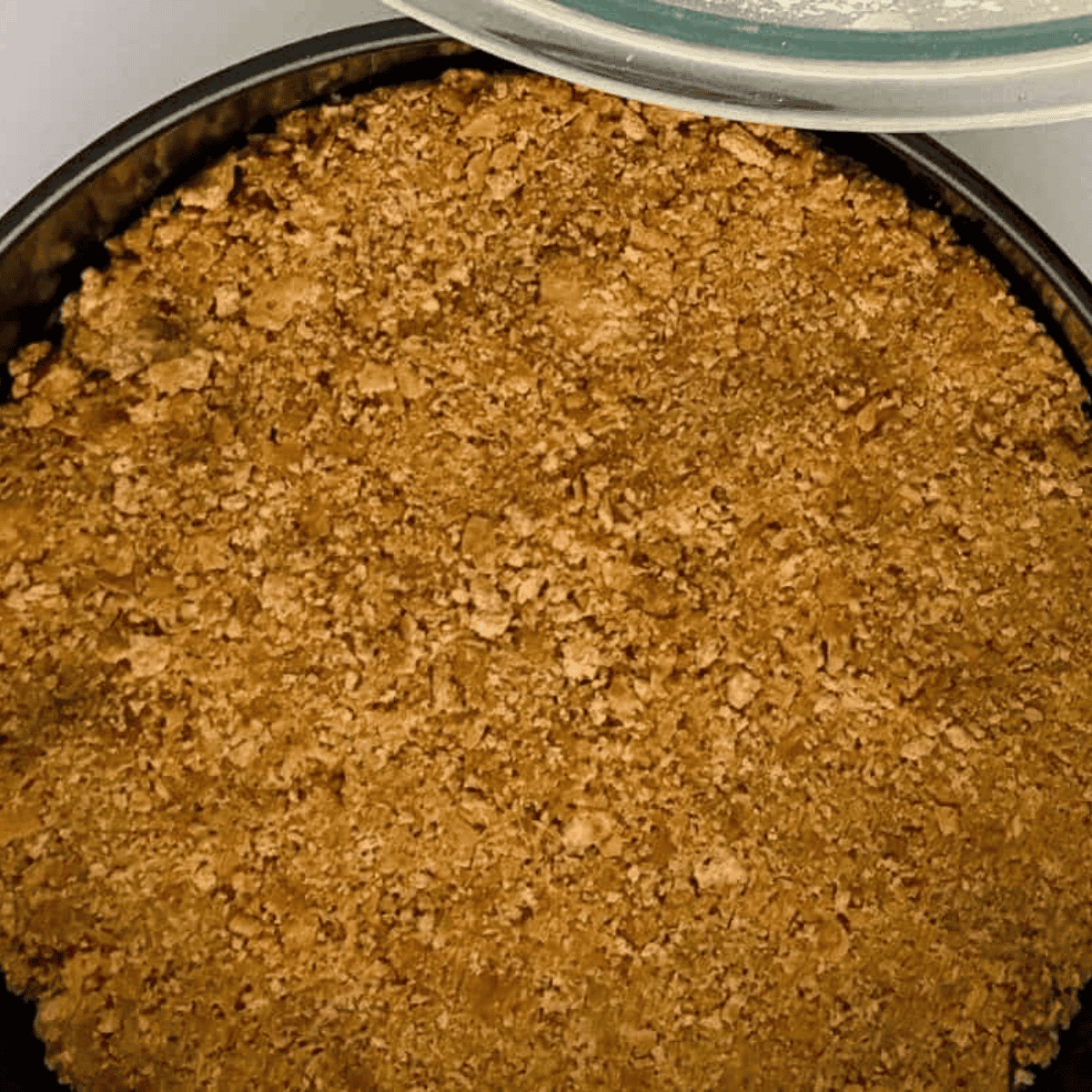 Mixing graham cracker crumbs with melted butter and pressing into a springform pan for cheesecake crust.