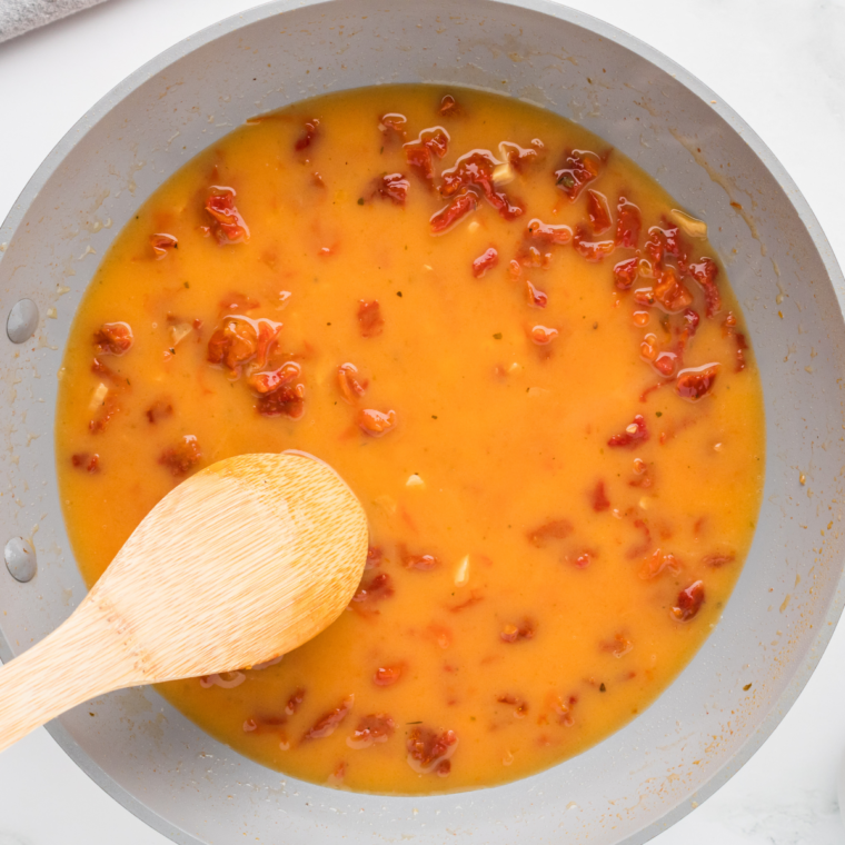Sautéing garlic in a saucepan with sun-dried tomatoes, white wine, and lemon juice, finished with whisked butter for a creamy sauce.