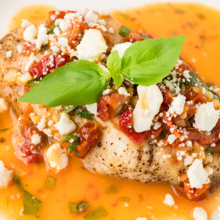 Copycat Carrabba's Chicken Bryan with lemon butter sauce, goat cheese, and basil garnish served on a plate."