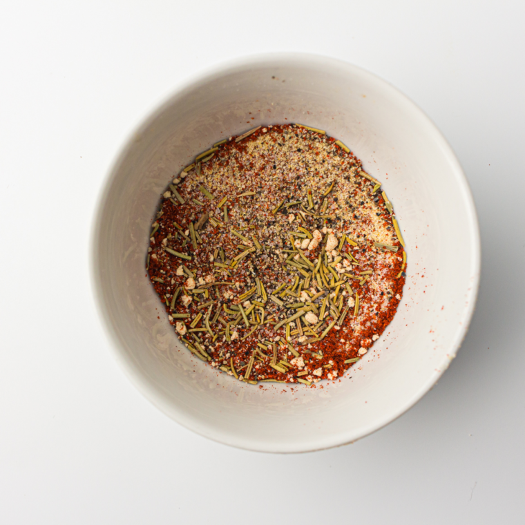 Mixing salt, black pepper, paprika, onion powder, garlic powder, thyme, oregano, rosemary, and cayenne pepper in a small bowl for seasoning.