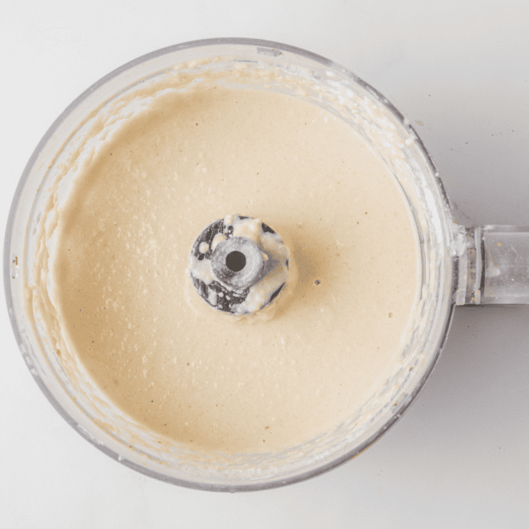 Ingredients for keto hummus, including cauliflower or zucchini, tahini, olive oil, lemon juice, garlic, and spices, blending in a food processor until smooth and creamy.