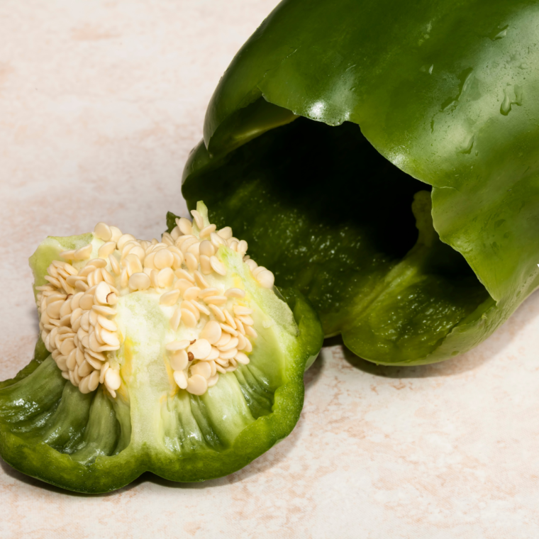 Preparing bell peppers by cutting off tops and removing seeds.