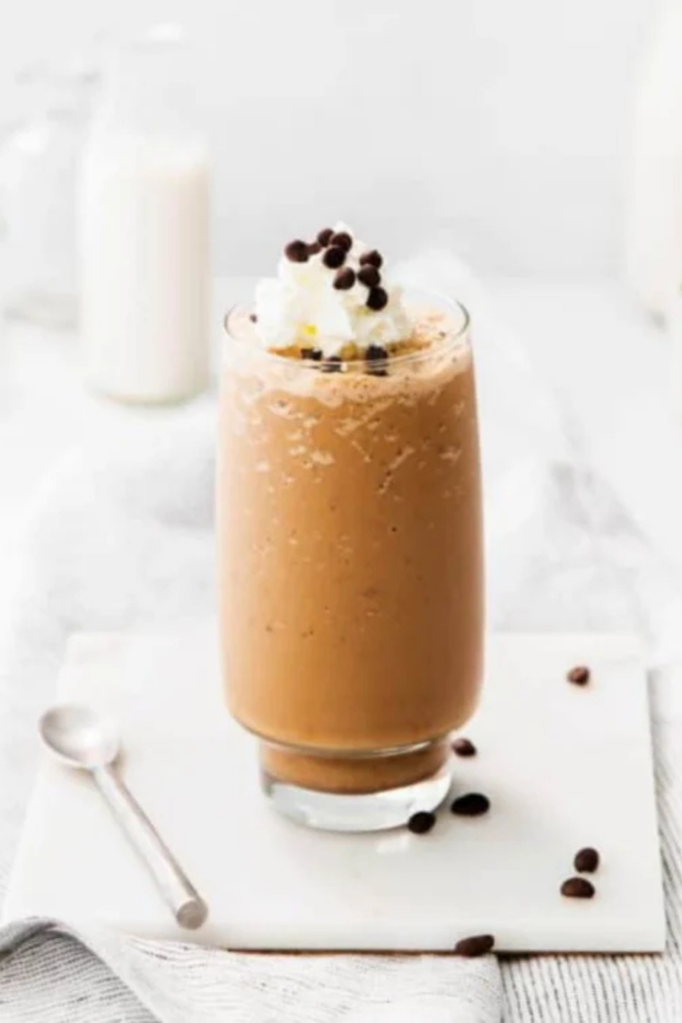 Ninja Creami frappuccino topped with whipped cream, chocolate drizzle, and java chips in a tall glass