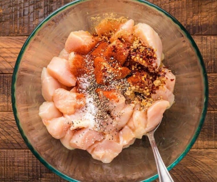 process of making air fried chicken bites - mixing chicken with seasonings and spices.