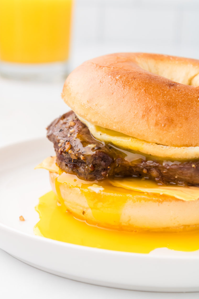 "Stacking the juicy steak, fluffy eggs, and melted cheese on the toasted bagel."