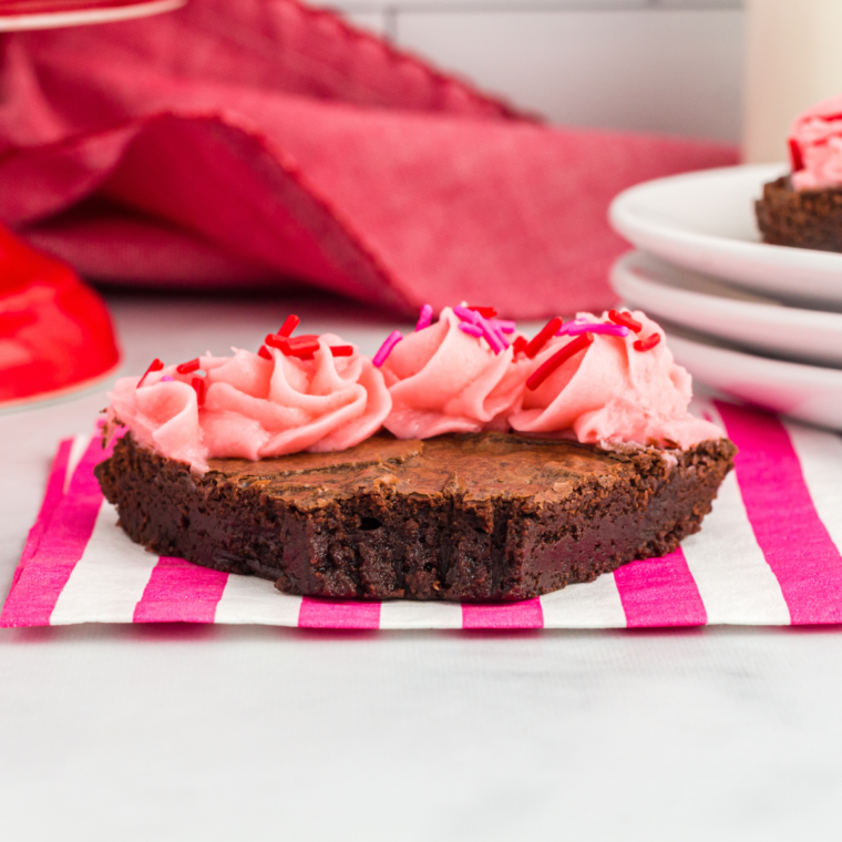 Air fryer brownie pizza with pink frosting on a red plate, cut into six wedges