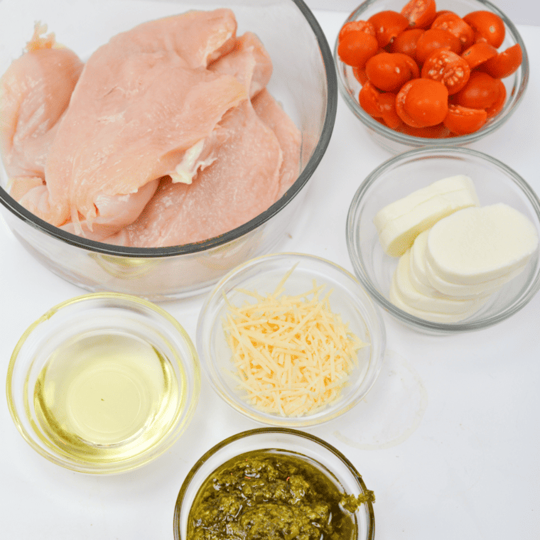 2 Large boneless skinless chicken breasts cut in half lengthwise
1 Tbsp. Olive oil
1 Pint cherry tomatoes halved
¼ C. Pesto sauce
6 oz. Sliced fresh mozzarella
Salt and pepper to taste
2 Tbsp. Shredded parmesan for garnish
Chopped basil for garnish
Tin foil