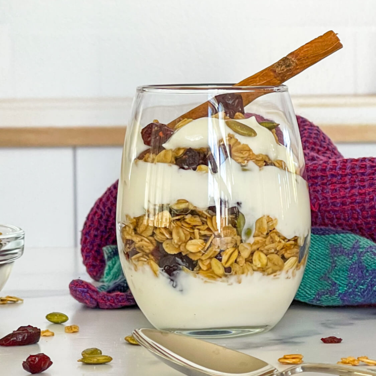 Cranberry Granola in a glass with vanilla yogurt on top, making a parfait.