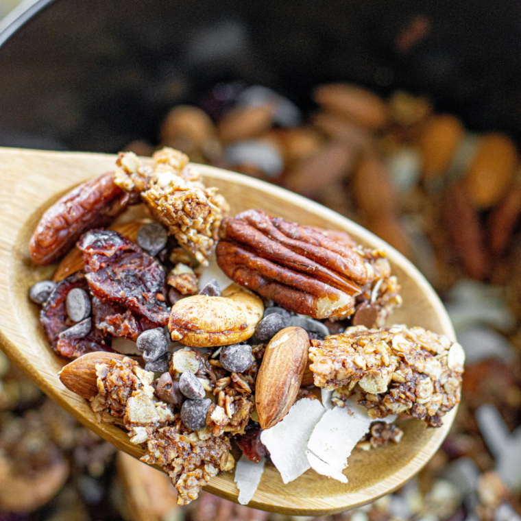 Scoop of Cranberry Granola on wooden spoon, being shown to the audience