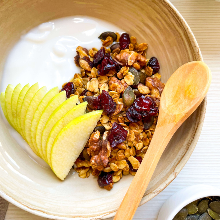 Cranberry Granola being served with vanilla yogurt in a brown bowl