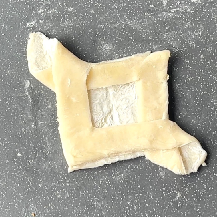 Puff pastry rolled into a 12"x12" square on a floured surface, cut into 9 equal squares with a knife.