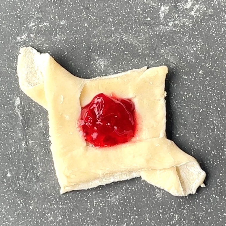 Pastry squares with raspberry preserves in the center, brushed with beaten egg for a golden glaze.