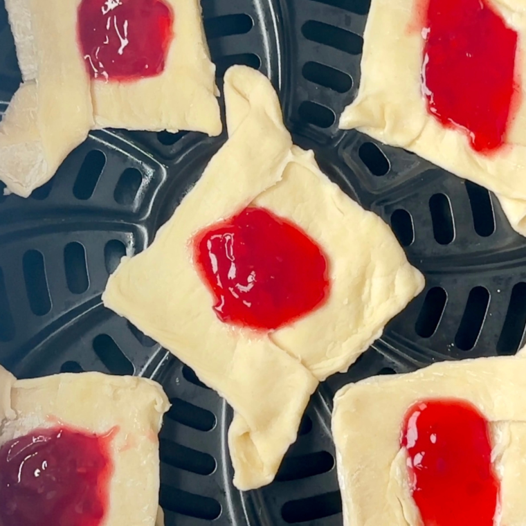 Puff pastry brushed with beaten egg, placed in the air fryer at 350°F, cooked until golden brown, then sliced into pieces and served warm.