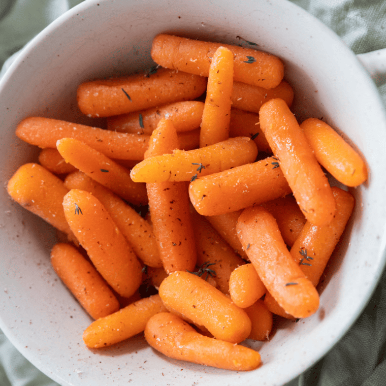 Pouring the sauce over the baby carrots in a saucepan for Cracker Barrel Carrots recipe.