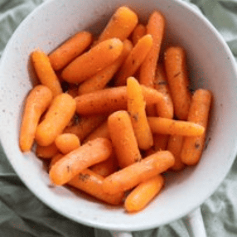 A serving of glazed Cracker Barrel carrots, showcasing tender orange carrots coated in a sweet sauce, garnished with fresh herbs.