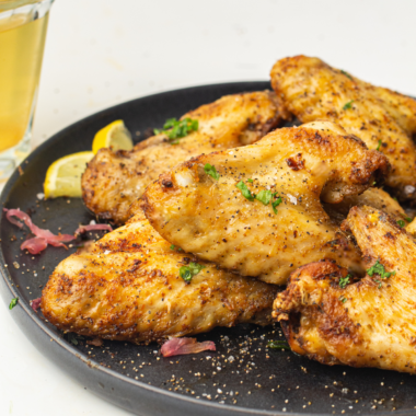 Plate of Ninja Crispi frozen chicken wings, cooked crispy and tossed in buffalo sauce, served on a black plate