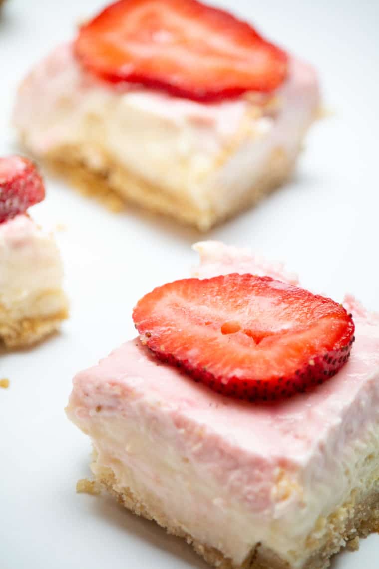 Air Fryer Strawberry Cheesecake Bars served on a plate with fresh strawberry slices and a golden graham