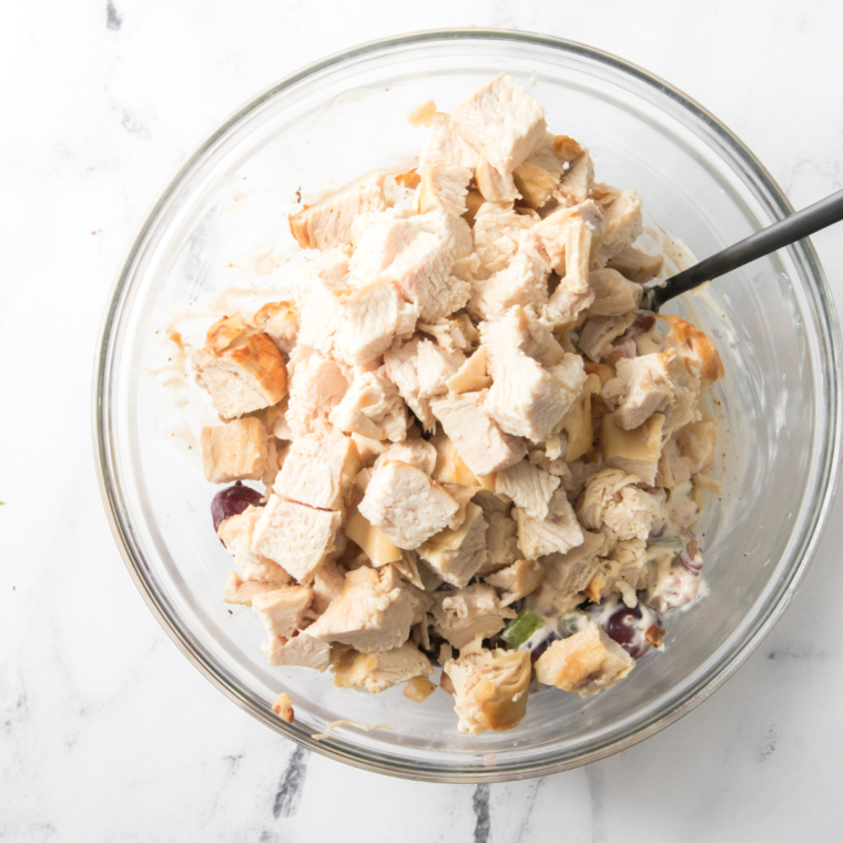 Shredded chicken added to a glass mixing bowl