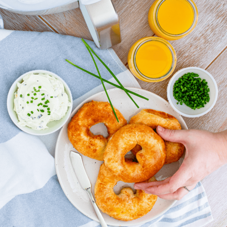 "Homemade Air Fryer Bagels topped with cream chese on a plate"
