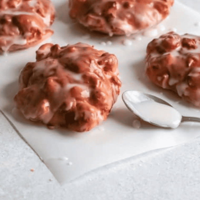 Air fryer apple fritters drizzled with vanilla glaze and powdered sugar
