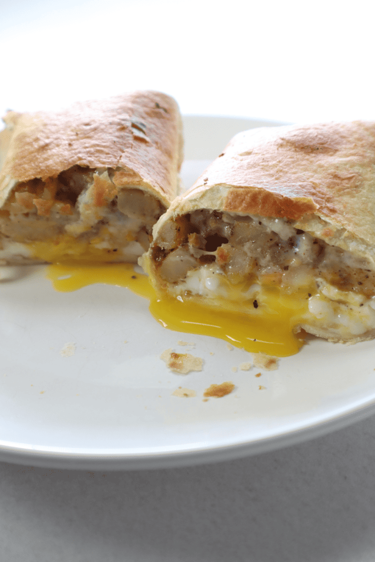 Air Fryer Barn Yard Buster Wrap filled with sausage, potatoes, scrambled eggs, cheddar cheese, and gravy, golden and crispy on the outside.