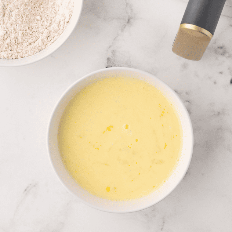 Whisking together buttermilk, beer, and eggs in a bowl for Air Fryer Beer Battered Onion Rings.