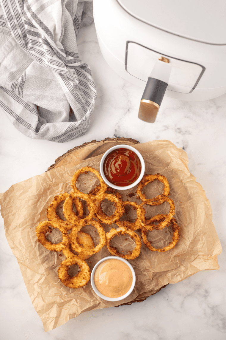 Golden and crispy beer battered onion rings cooked in the air fryer, served on a plate.