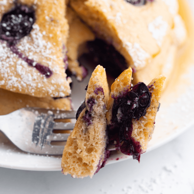 Fluffy air fryer blueberry pancakes stacked with fresh blueberries and syrup on top