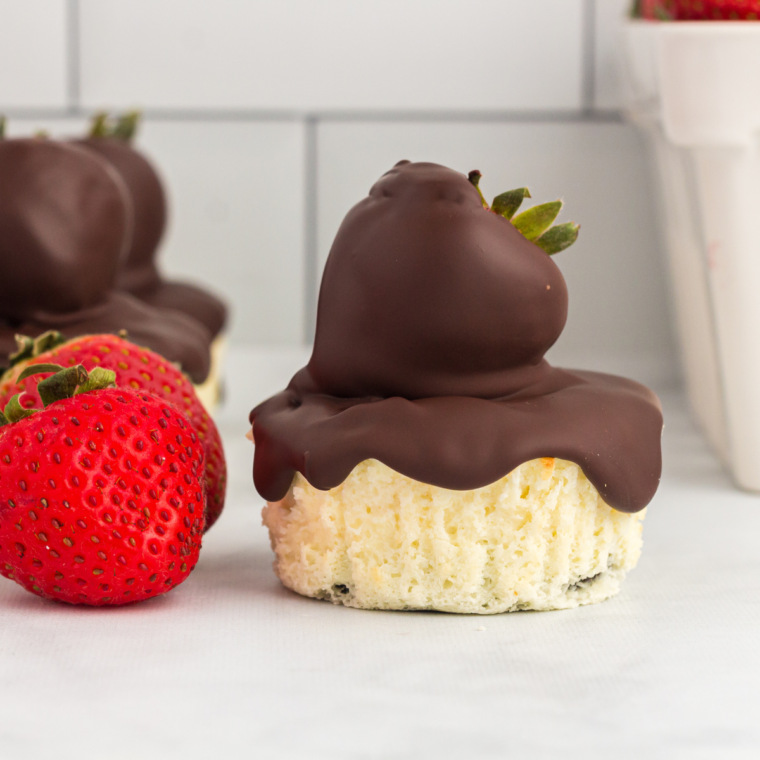 Close-up of a mini cheesecake with an Oreo crust and a chocolate-dipped strawberry on top