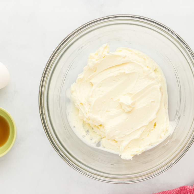 Beating cream cheese, sugar, egg, and sour cream into a smooth cheesecake batter