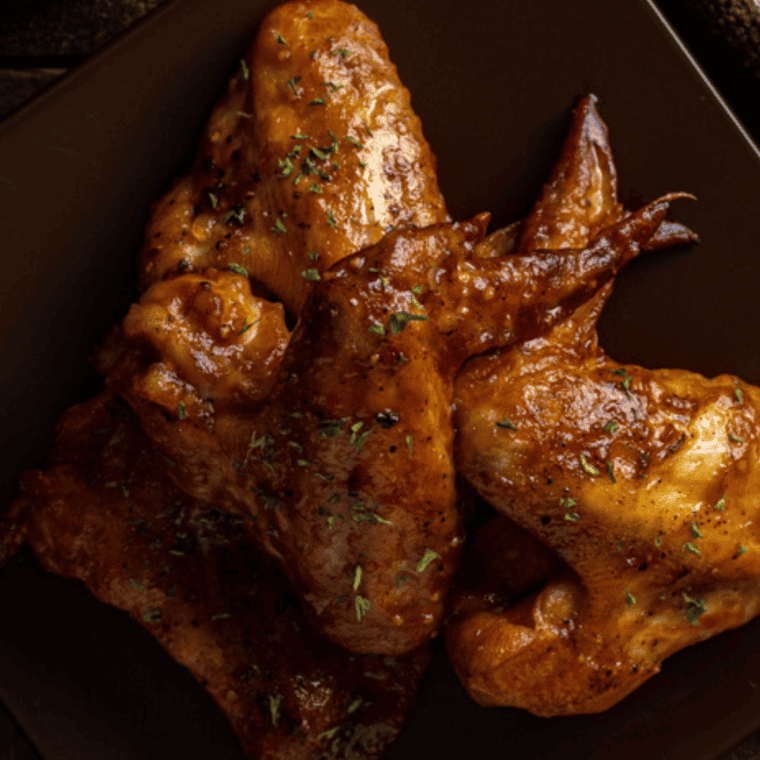 Close-up of crispy Air Fryer Coca Cola Wings with a shiny glaze, served on a platter.