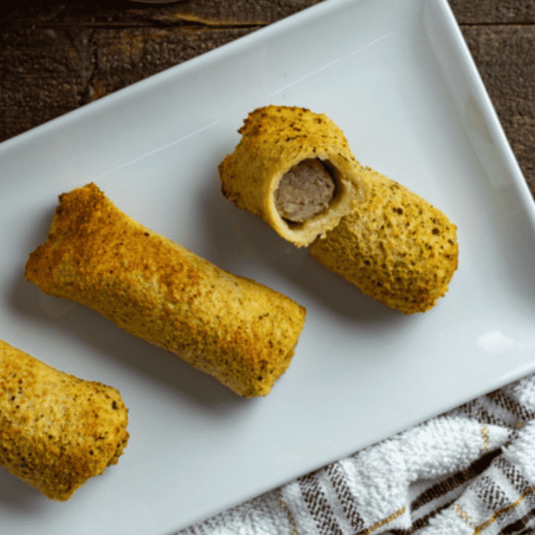 Close-up of a French toast sausage roll-up cut in half showing the sausage center
