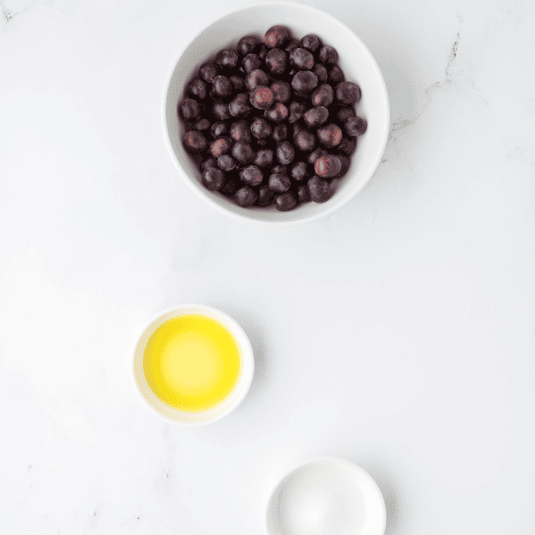 Fresh grapes, olive oil, and optional seasonings arranged on a kitchen table, ready to be made into crispy air fryer grapes.