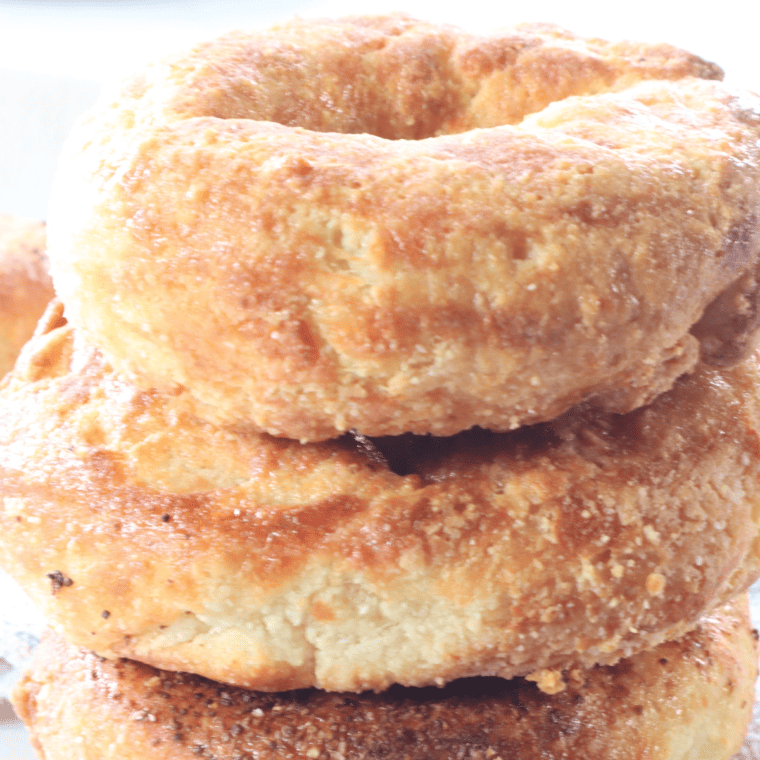 Two hands tearing a warm air fryer keto bagel in half showing the steamy chewy fathead dough interior.