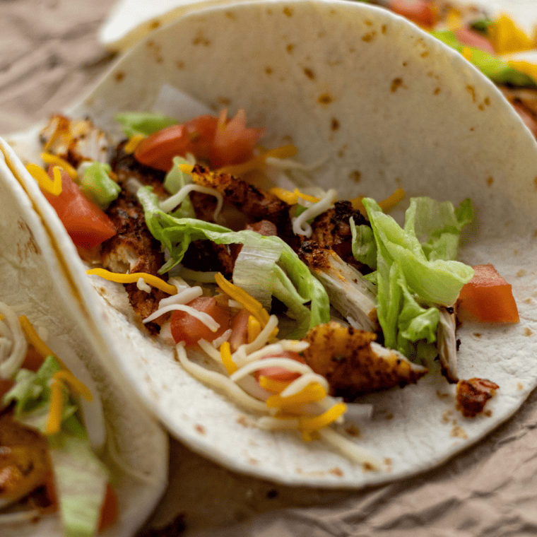 Crispy air fryer chicken tacos with golden, charred edges on a small corn tortilla