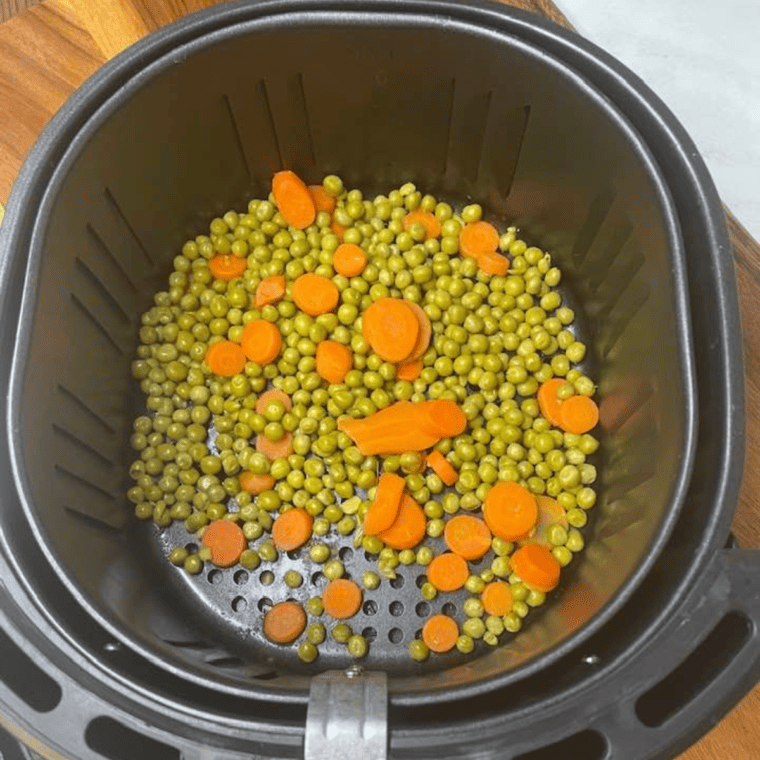 Air Fryer Peas and Carrots in the air fryer basket. Fully cooked.