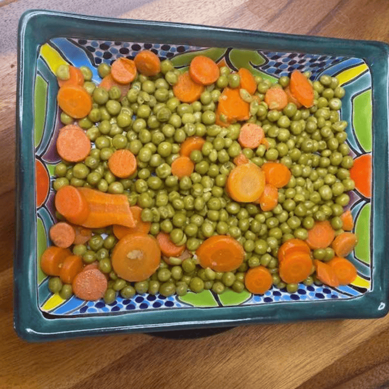Air fryer peas and carrots garnished with herbs"