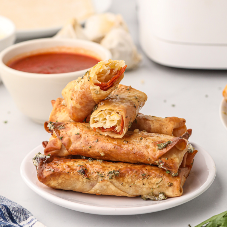 Air fryer pizza egg roll cut in half showing melty mozzarella cheese and pepperoni filling pull