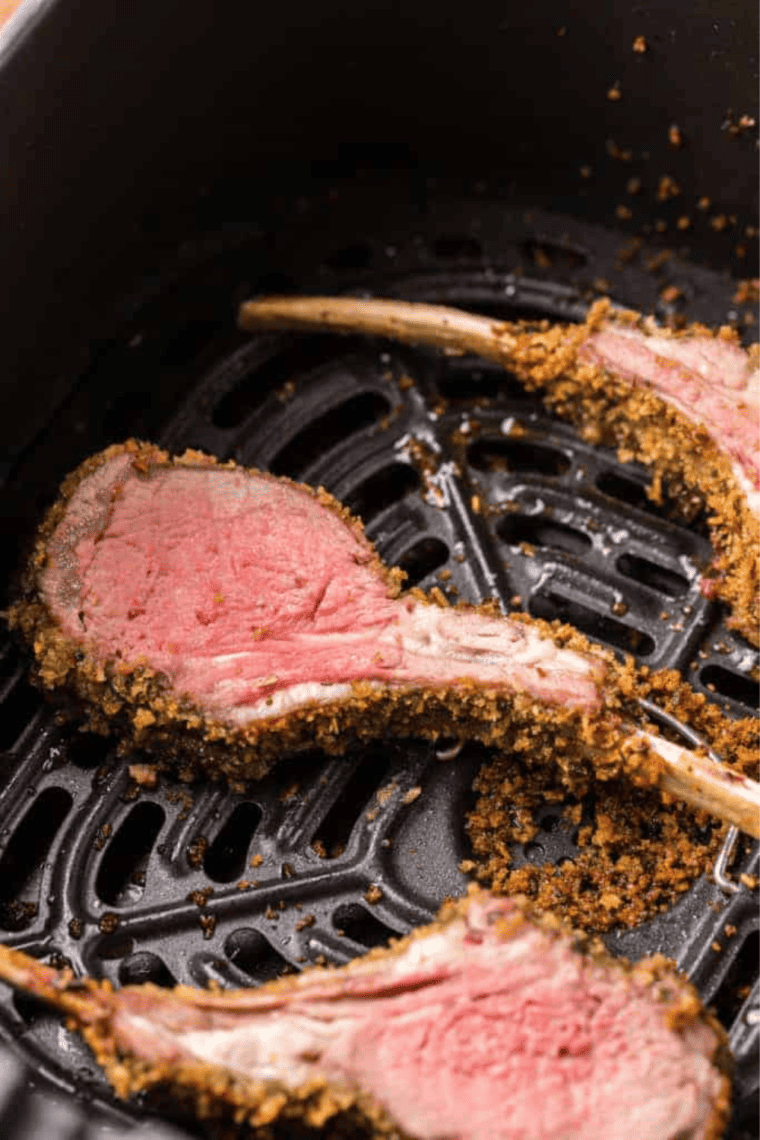 Air fryer rack of lamb with a crispy exterior and tender interior, garnished with fresh herbs, ready to be served.
