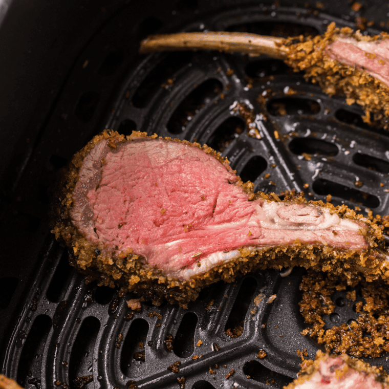 Golden-brown Air Fryer Rack of Lamb garnished with fresh rosemary on a white plate, ready to serve.