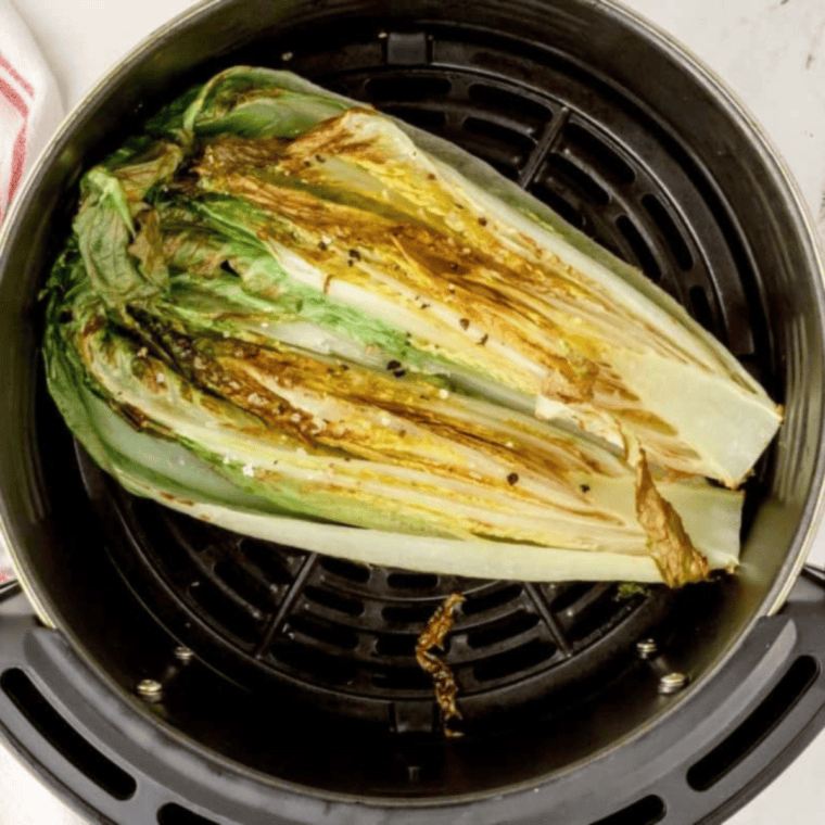Cooked romaine lettuce in the air fryer basket.