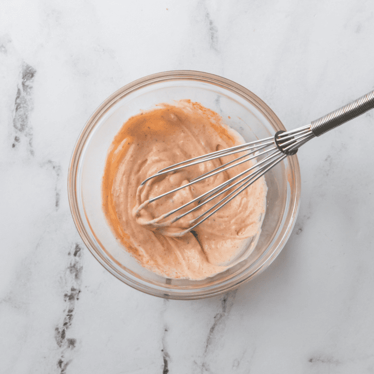 Stirring dill pickle juice into the creamy sauce base