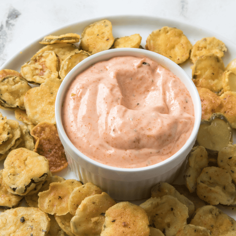 Close-up of crispy fried pickles served with creamy dipping sauce
